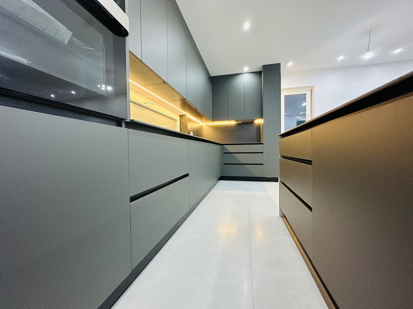 Cuisine noire veinée marbre avec îlot central et vitrines rétro-éclairées